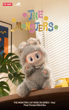 Load image into Gallery viewer, A plush cat monster toy wearing a gray furry monster costume sits on a wooden surface in a styled room scene with blinds, a plant, and colorful 'THE MONSTERS' lettering above. Pop Mart branding is visible.