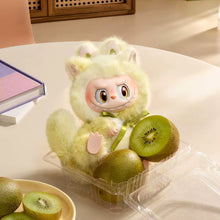 Load image into Gallery viewer, A plush toy dressed in a fluffy cream-colored animal costume sits on a table, surrounded by kiwi fruit in a clear plastic container. The scene is styled with a book and a small plate of kiwi slices in a warm indoor setting.
