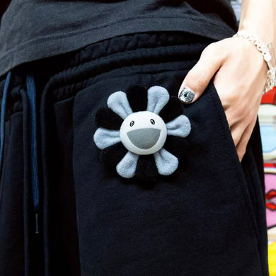 Black jacket with a smiley face design on the pocket, held by a person.